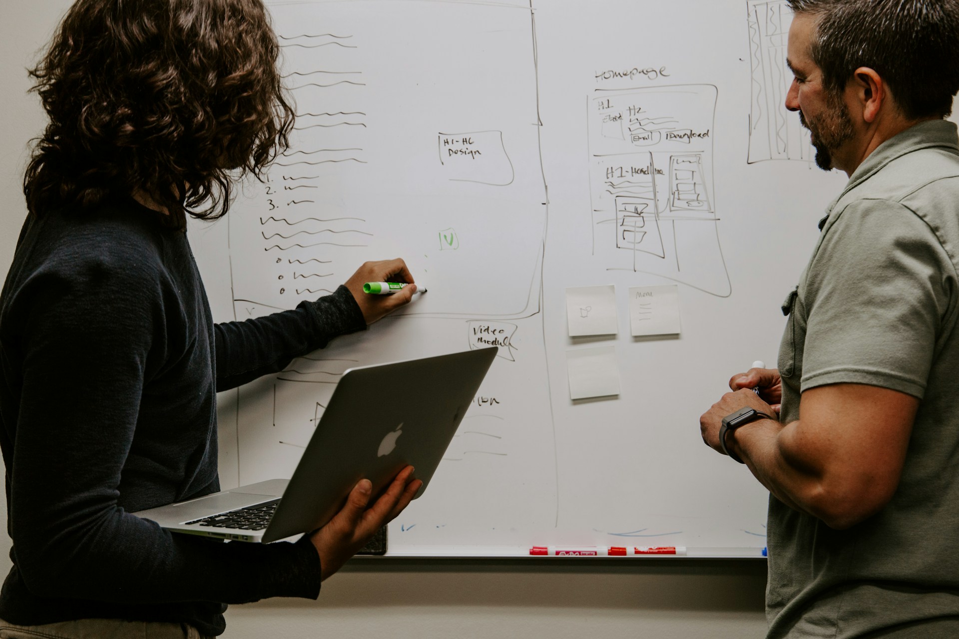 Colleagues mapping out a project plan on a whiteboard