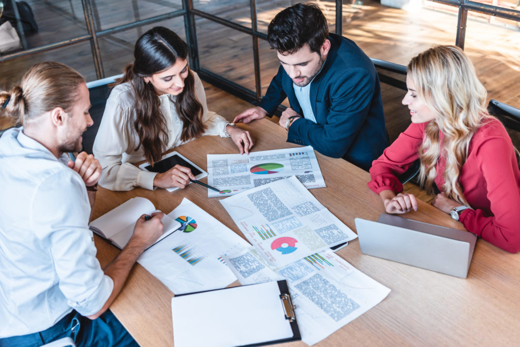 Team reviewing printed charts and reports spread across a table