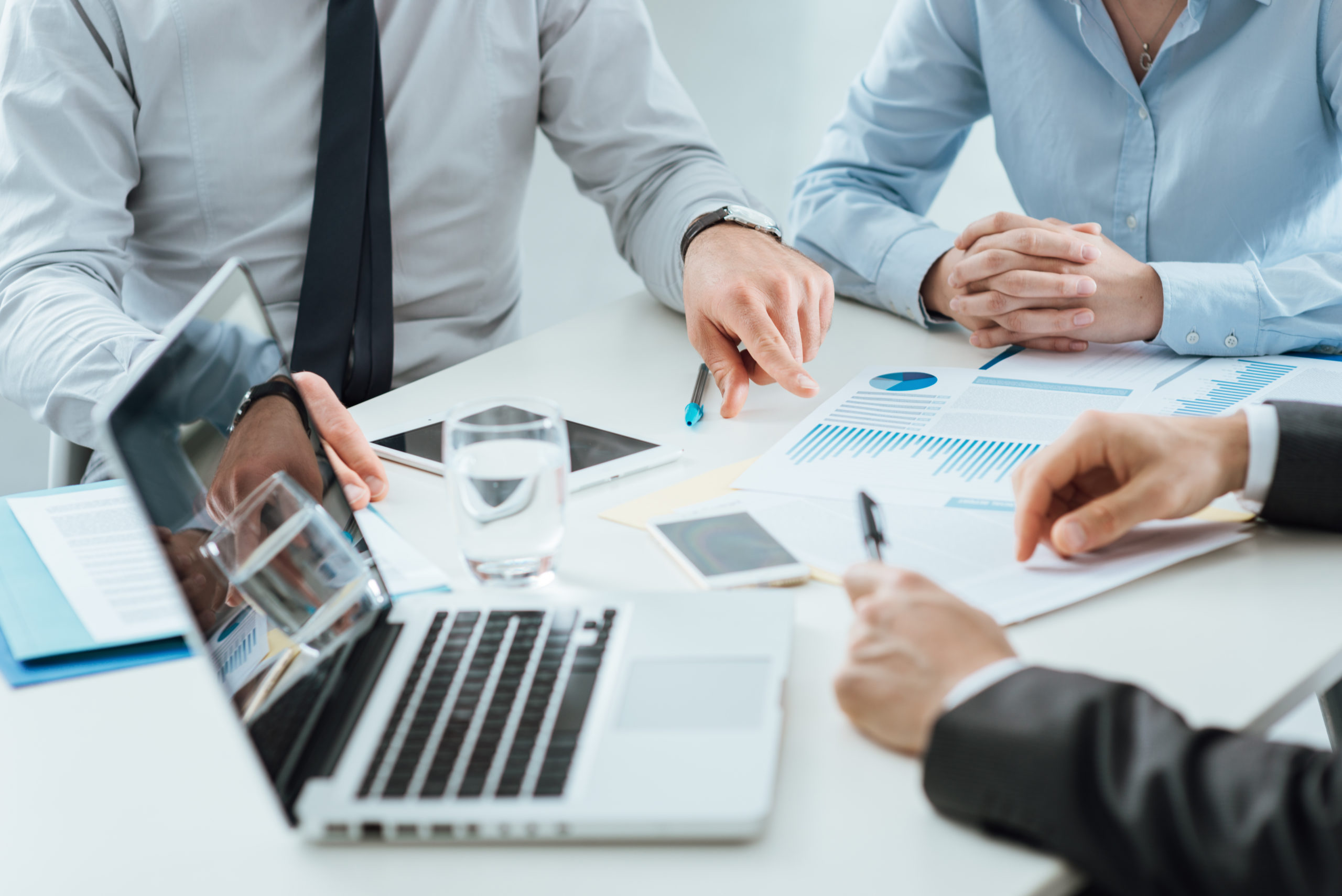 Businesspeople reviewing financial charts and a laptop at a meeting table